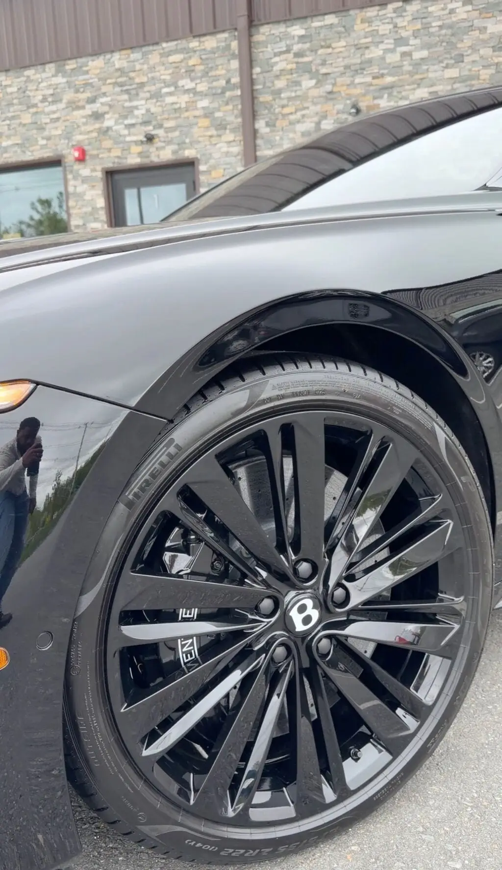 Close-up of a 22 inch gloss black Bentley wheel with a glass-like ceramic coated finish reflecting overhead lights at Secret Touch Auto Spa Shrewsbury MA