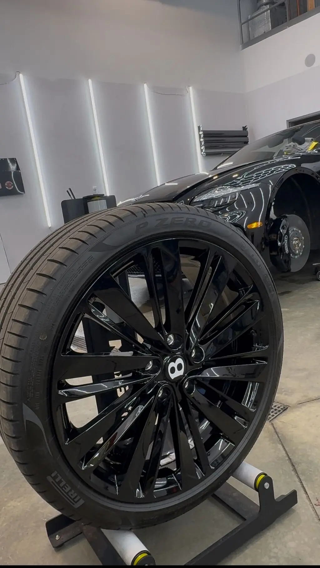 Bentley wheel and tire removed from the vehicle and resting on a detailing stand during ceramic coating prep at Secret Touch Auto Spa in Shrewsbury Massachusetts